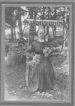 SA0021 - Eldress Margaret Egeson was from the South Family. Photo shows her seated in a chair outside near a swing holding flowers.  Identified on reverse., Winterthur Shaker Photograph and Post Card Collection 1851 to 1921c